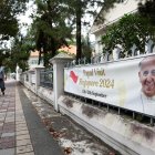 La gente pasa junto a una pancarta que da la bienvenida al Papa Francisco antes de su llegada a Singapur, el 11 de septiembre de 2024.