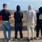 Adam (d) y otros jóvenes miran hacia Ceuta en una carretera a un kilómetro de Fnideq (Castillejos).
