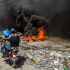 Puerto Príncipe. Dos hombres pasan frente a barricada con fuego.