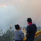 Dos pobladores observan las llamas sobre el bosque en Guápulo.