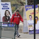 Un hombre camina frente a un afiche con propaganda electoral.