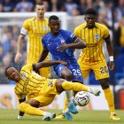 Pervis Estupiñán (piso) de Broghton defiende la pelota ante Moisés Caicedo (c) de Chelsea