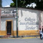 Una mujer camina junto a su hijo frente al colegio San Francisco Javier, este jueves en Caracas (Venezuela).