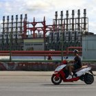 Un hombre en una moto eléctrica pasa frente a una de las plantas de generación eléctrica que permanece este domingo 20 de octubre, en el puerto de La Habana (Cuba).