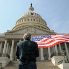 Un hombre con una bandera de los Estados Unidos delante del Capitolio en Washington.