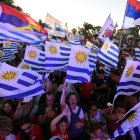 Simpatizantes del candidato por el partido Frente Amplio, Yamandu Orsi, ondean banderas uruguayas y del partido mientras asisten a su mitin de cierre de campaña.