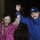 El presidente Daniel Ortega (R), y su esposa, la vicepresidenta Rosario Murillo, hacen un gesto ante la multitud durante la inauguración del paso elevado de Nejapa en Managua.