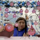 Una mujer observa esferas de vidrio soplado hechas por artesanos mexicano.