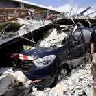 Pamandzi (Mayotte). Un gendarme francés observa el coche de la Gendarmería bajo edificios derrumbados