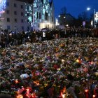 Los dolientes se ubican alrededor de monumento improvisado con flores y velas para las víctimas de un ataque con coche en un mercado navideño en Magdeburgo.