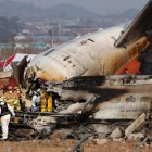Los bomberos trabajan en los restos del avión Jeju Air siniestrado este domingo 29 de diciembre en el aeropuerto surcoreano de Muan.