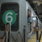 Una persona aparece asomada del otro lado de la ventana de un vagón del metro de Nueva York.