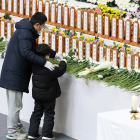 Un niño y su padre colocan una flor en un gimnasio de Muan, condado de Muan, Corea del Sur.
