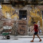 Un hombre pasa junto a un grafiti que dice "Tienes que ser feliz" del artista cubano Mr. Sad en La Habana.