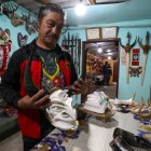 El artesano Ángel Velasco sostiene una mascara en Píllaro
