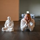 El artista Hong Jinshi posa junto a una escultura del presidente electo Donald Trump, en una pose que evoca a Buda en su taller en Xiamen.