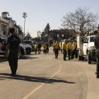 Un edificio carbonizado se ve a lo lejos mientras los empleados de una compañía privada de extinción de incendios, trabajan.