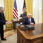El presidente de Estados Unidos, Donald Trump (derecha), firma órdenes ejecutivas en la Oficina Oval de la Casa Blanca en Washington, DC.