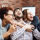 Colleagues rejoicing their work, shouting, embracing at business meeting.