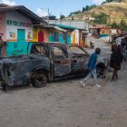 La gente camina junto a un vehículo quemado en Kenscoff, Haití, el 29 de enero de 2025.