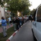 Personas y personal del Centro Médico Shamir frente al complejo hospitalario de Beer Yaakov, ondean banderas mientras llegan ambulancias de la policía que transportan a cinco rehenes recién liberados.