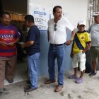 Hombres esperan para votar este domingo, en un puesto de votación en Olón (Ecuador).