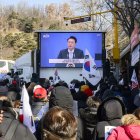 Los partidarios miran imágenes de archivo de los discursos del líder surcoreano Yoon Suk Yeol (C) en una pantalla cerca del Tribunal del Distrito Central en Seúl el 20 de febrero de 2025.