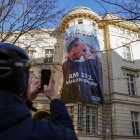Un hombre toma una fotografía del cartel que muestra el inicio de un beso entre el favorito de las encuestas, el líder conservador Friedrich Merz, y la candidata ultraderechista Alice Weidel, en Berlín, el 20 de febrero de 2025.