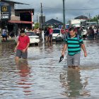 Ciudadanos caminan entre el agua acumulada en una vía en la parroquia Calderón, en Portoviejo, zona rural de Portoviejo.