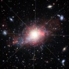 La ilustración artística muestra una galaxia enana que alberga un núcleo galáctico activo, y en el fondo hay muchas otras galaxias enanas que albergan agujeros negros activos,