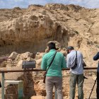 Visitantes que observan un yacimiento al pie de la cordillera de Jebel Faya, en el desierto emiratí de Sharjah.