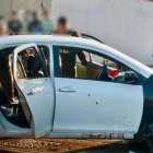 Agentes policiales custodian un vehículo involucrado en la masacre ocurrida en Socio Vivienda 2, la tarde del jueves 6 de marzo.