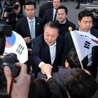 El presidente destituido, Yoon Suk Yeol, estrecha la mano de un partidario al llegar frente a su residencia oficial después de ser liberado de su detención, el 8 de marzo de 2025.