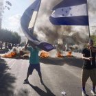Simpatizantes del Partido Nacional de Honduras ondeando banderas y quemando llantas en una calle, con la exigencia que llegaran urnas de votación a su barrio en Tegucigalpa (Honduras).