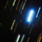 Imagen compuesta del asteroide 2024 YR4 capturada con el telescopio Gemini Sur (Chile) en febrero de 2025. El asteroide es el punto nebuloso en el centro de la imagen, que está rodeado de coloridas estelas de estrellas, las cuales muestran el paso del tiempo y el movimiento del cielo nocturno en una imagen fija.