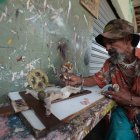 Gustavo Vera retoca la imagen de Cristo crucificado en los exteriores de un taller en General Gómez y Los Ríos. En el sitio se realiza esta actividad desde hace más de 50 años.