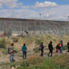 Migrantes caminan cerca del muro que separa la frontera estadounidense en Ciudad Juárez, Chihuahua (México).
