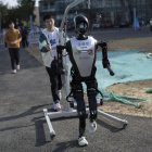 Un técnico camina detrás de un robot humanoide antes de la carrera de humanos y robots en Pekín.