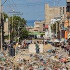 decenas de personas al caminar por una calle en ruinas y llena de basura cerca al Palacio Nacional, en Puerto Príncipe (Haití).