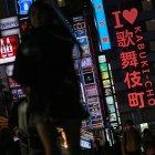 Personas caminando por una calle junto al letrero de neón "I love Kabukicho" en la zona de entretenimiento del distrito rojo