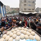 Palestinos se reúnen para recibir una comida caliente en un centro de distribución de alimentos en el campamento de refugiados de Nuseirat