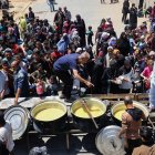 Palestinos desplazados hacen cola para recibir una porción de comida caliente en un comedor benéfico en el campo de refugiados de Nuseirat, en el centro de la Franja de Gaza, el 5 de mayo de 2025.