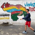 Fotografía del 2 de abril del 2025 de una persona caminando frente a un mural con el mapa de Venezuela en Caracas (Venezuela).