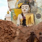 Fotografía del 12 de abril de 2025 muestra a un hombre retirando escombros alrededor de una dañada estatua de Buda