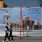 AME6509. LIMA (PERÚ), 10/05/2025.- Personas pasan frente a una pancarta con la imagen del papa León XIV este sábado, en la Plaza de Armas en Chiclayo (Péru). Rebosa la actividad en la plaza central de Chiclayo, localidad peruana donde el nuevo papa fue obispo ocho años y en la que los obreros ultiman las pantallas gigantes que retransmitirán una gran misa multitudinaria de acción de gracias de este sábado por la noche, mientras la Policía ultima las medidas de seguridad. EFE/ Paolo Aguilar