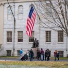 Las personas se reúnen alrededor de la estatua de John Harvard en el campus de la Universidad de Harvard en Cambridge, Massachusetts, el 15 de abril de 2025.