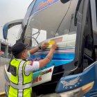 Un agente de la CTE coloca un sticker en uno de los buses sancionados, la mañana de este jueves 22 de mayo.