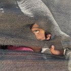 Una niña se asoma tras una tienda improvisada en el puerto en la Ciudad de Gaza, donde miles de personas desplazadas por los ataques israelíes han encontrado refugio, el 20 de mayo de 2025.