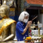 Una mujer usando mascarilla durante una visita a un sitio budista en Bangkok, Tailandia.