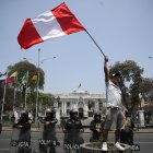 Fotografía de un hombre al ondear una bandera peruana, frente a la sede del Congreso Nacional de Perú, en Lima (Perú).